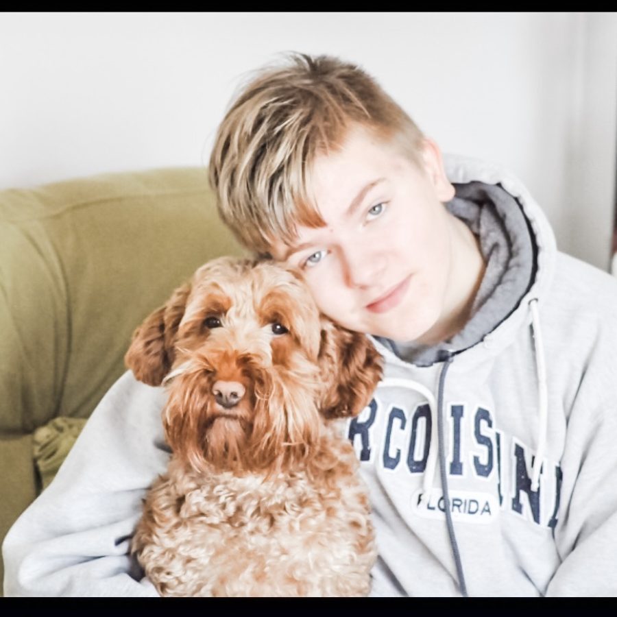 Boy hugging red dog.